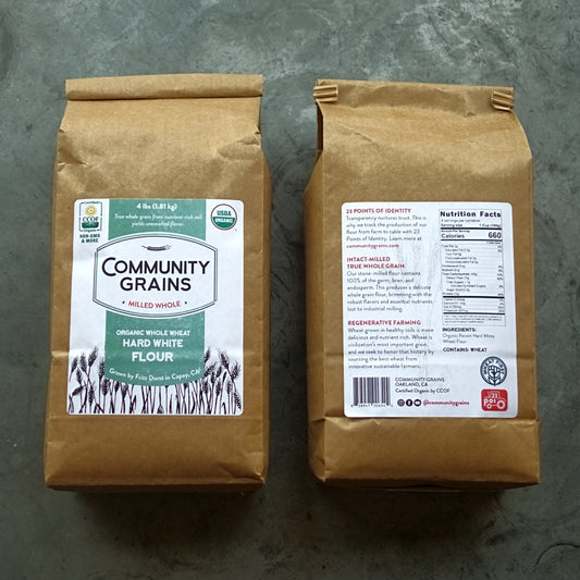 Two brown bags of Community Grains flour on a gray surface